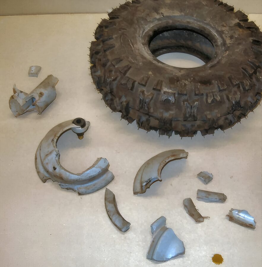 Fractured wheel rim in pieces beside its tire